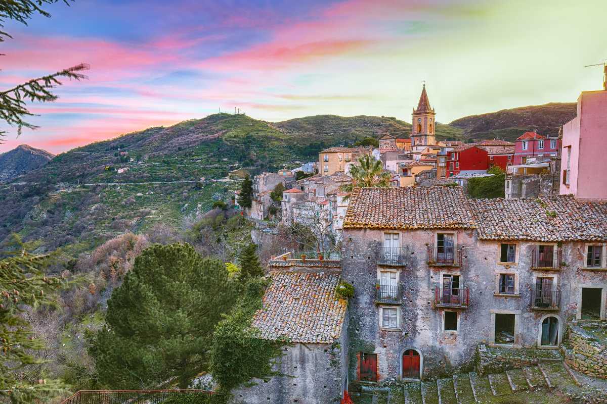 Vista panoramica dal Monte Orlando, con il borgo medievale di Gaeta, il Golfo e il mare scintillante al tramonto. Atmosfera suggestiva, colori caldi.
